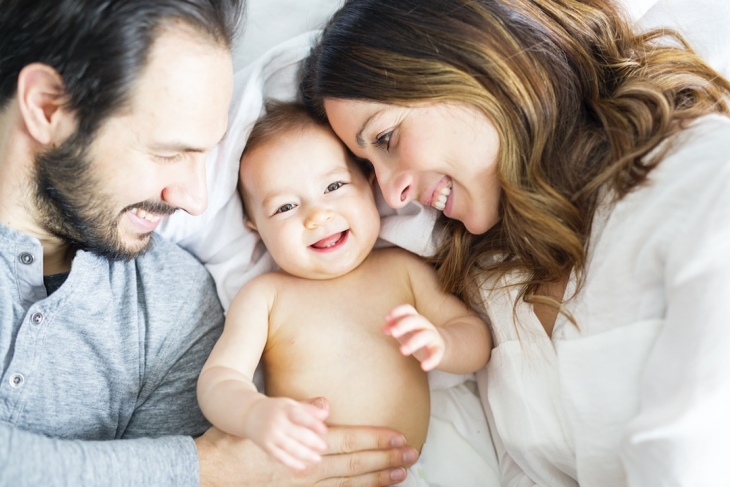 bébé souriant au milieu de ses parents